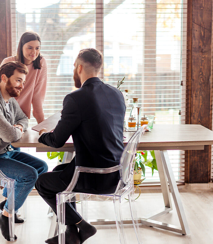Meet Our Team - Professional and Welcoming Group at a Conference Table Faces the Camera, Team Leader Sitting on the Table with Arms Folded